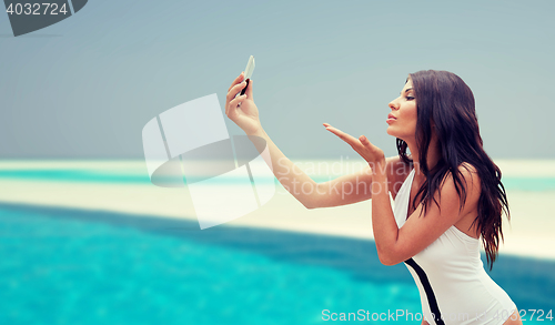 Image of young woman taking selfie with smartphone