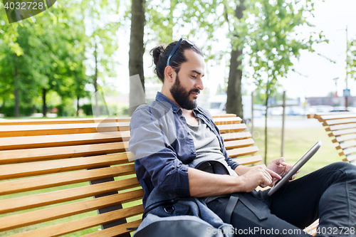 Image of man with tablet pc sitting on city street bench