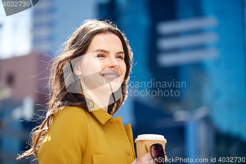 Image of happy young woman drinking coffee on city street