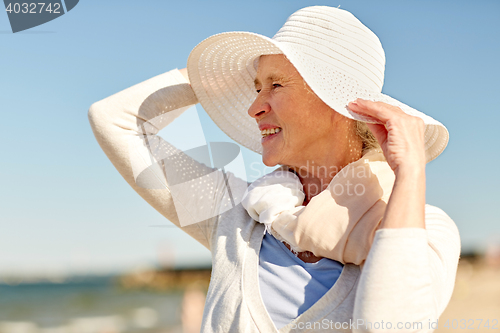 Image of happy senior woman in sun hat on summer beach