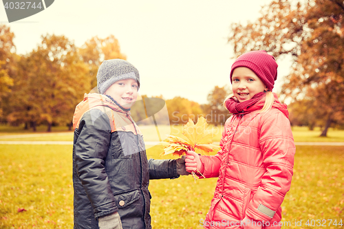 Image of little boy giving autumn maple leaves to girl