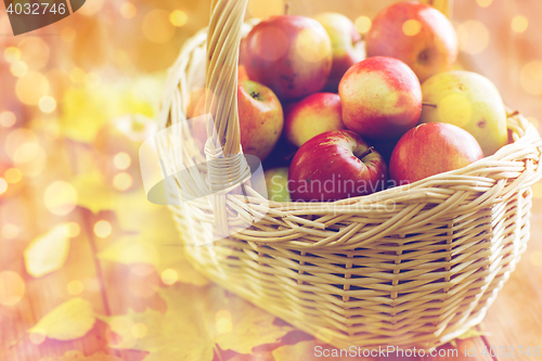 Image of close up of basket with apples on wooden table