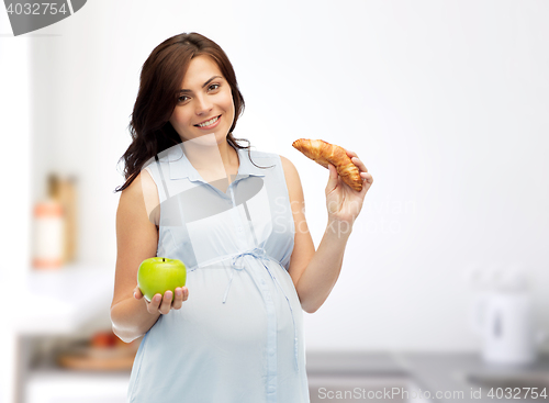 Image of happy pregnant woman with apple and croissant