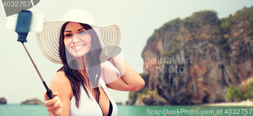 Image of smiling young woman taking selfie with smartphone