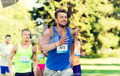 Image of happy young sportsmen racing wit badge numbers