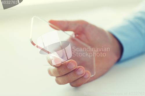 Image of close up of male hand with transparent smartphone