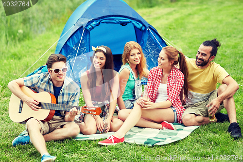 Image of happy friends with drinks and guitar at camping