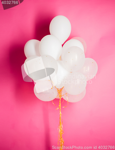 Image of close up of white helium balloons over pink