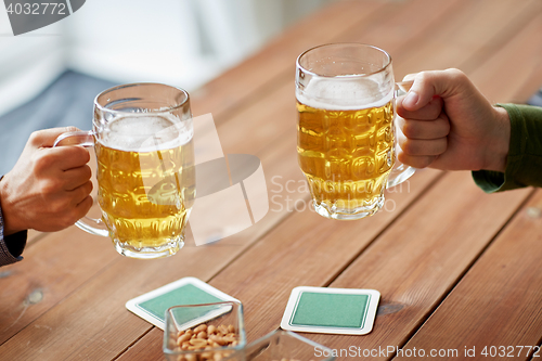 Image of close up of hands with beer mugs at bar or pub