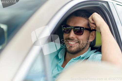 Image of happy smiling man in sunglasses driving car