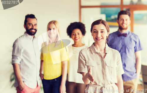 Image of woman making handshake over creative office team