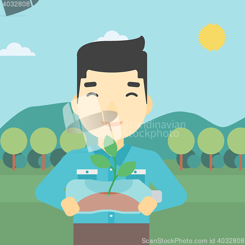 Image of Man holding plant growing in plastic bottle.