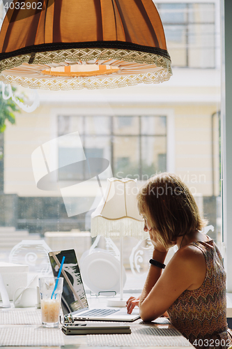 Image of Young short-haired woman using laptop in cafe