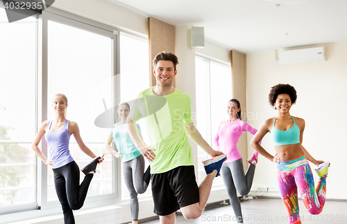 Image of group of smiling people exercising in gym