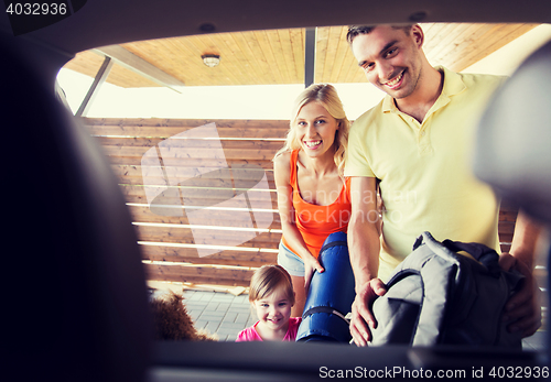 Image of happy family packing things to car at home parking