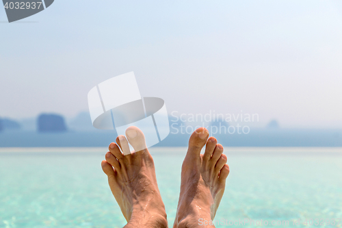 Image of closeup of male feet over sea and sky on beach