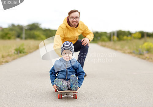 Image of happy father and little son riding on skateboard