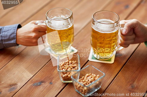 Image of close up of hands with beer mugs at bar or pub