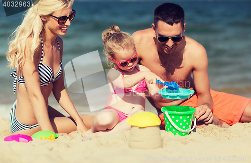 Image of happy family playing with sand toys on beach