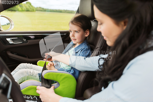 Image of happy woman fastening child with seat belt in car