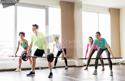 Image of happy people exercising with barbell bars in gym