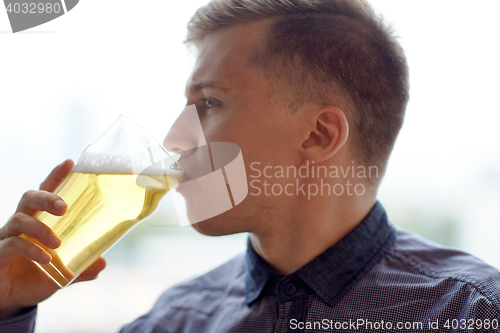 Image of close up of young man drinking beer from glass