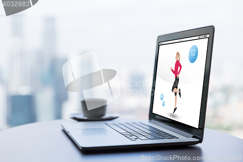 Image of close up of laptop with fitness app and coffee cup