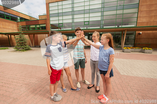 Image of group of children making high five at school yard