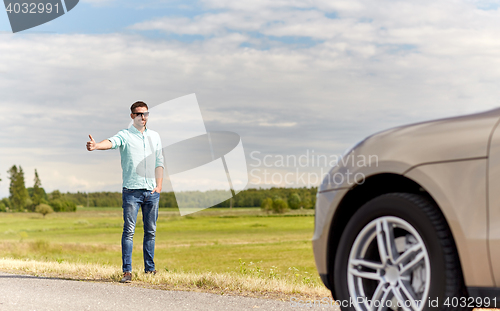 Image of man hitchhiking and stopping car at countryside