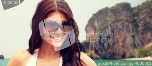 Image of smiling young woman with sunglasses on beach