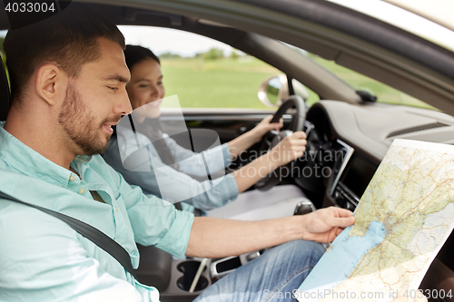 Image of happy man and woman with road map driving in car