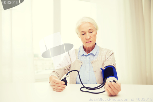 Image of old woman with tonometer checking blood pressure