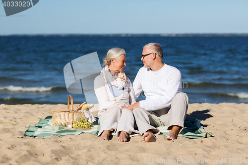 Image of happy senior couple having picnic on summer beach