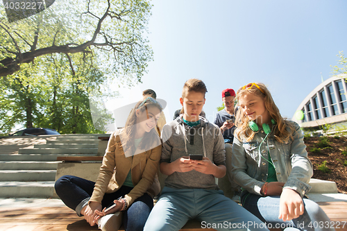 Image of happy teenage friends with smartphones outdoors