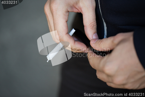 Image of close up of addict hands with marijuana joint