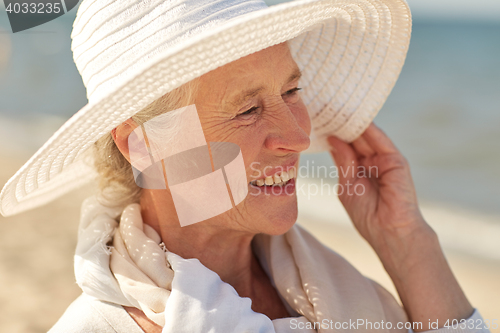 Image of happy senior woman in sun hat on summer beach