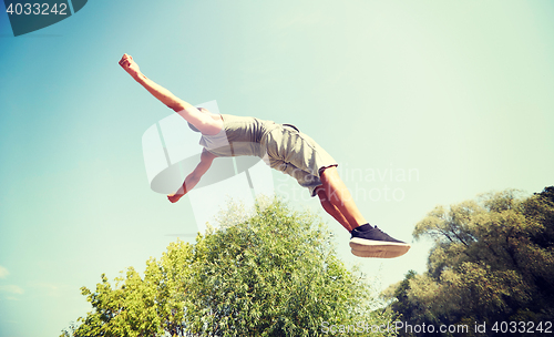 Image of sporty young man jumping in summer park