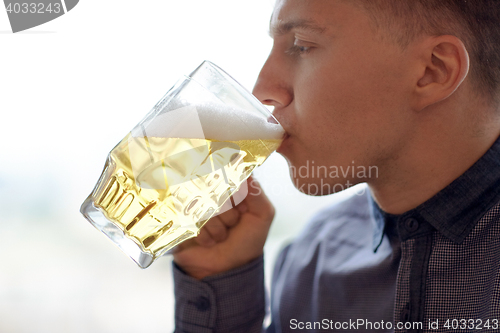 Image of close up of young man drinking beer from glass mug
