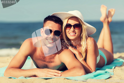 Image of happy couple in swimwear lying on summer beach