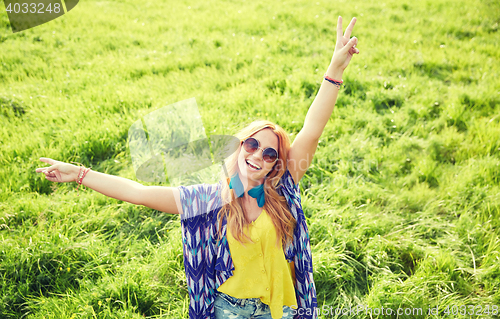 Image of smiling young hippie woman dancing on green field