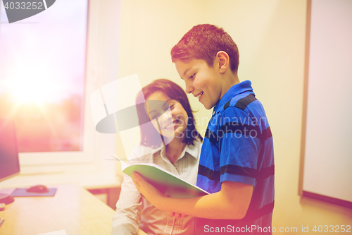 Image of school boy with notebook and teacher in classroom