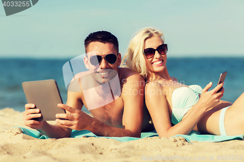 Image of happy couple with tablet pc sunbathing on beach