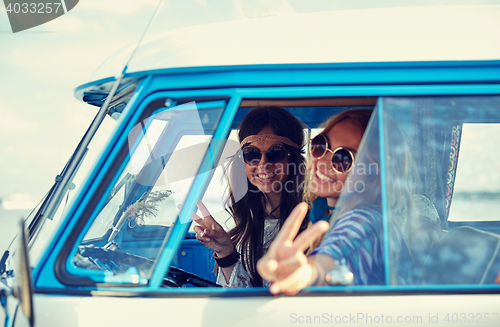 Image of smiling young hippie women driving minivan car