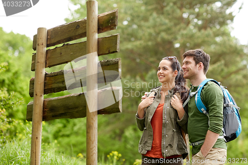 Image of smiling couple at signpost with backpacks hiking