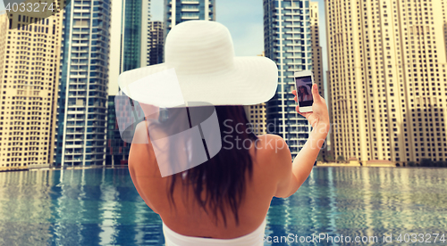 Image of woman taking selfie with smartphone over city pool