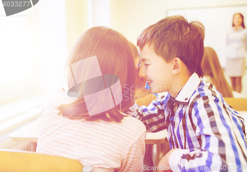 Image of smiling schoolgirl whispering to classmate ear