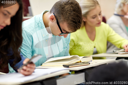 Image of male student in glasses reading book at lecture