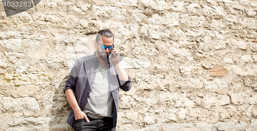 Image of smiling man with smartphone calling on city street