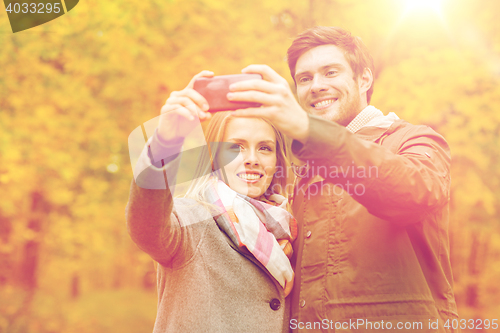 Image of smiling couple hugging in autumn park