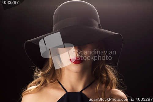 Image of beautiful woman in black hat over dark background